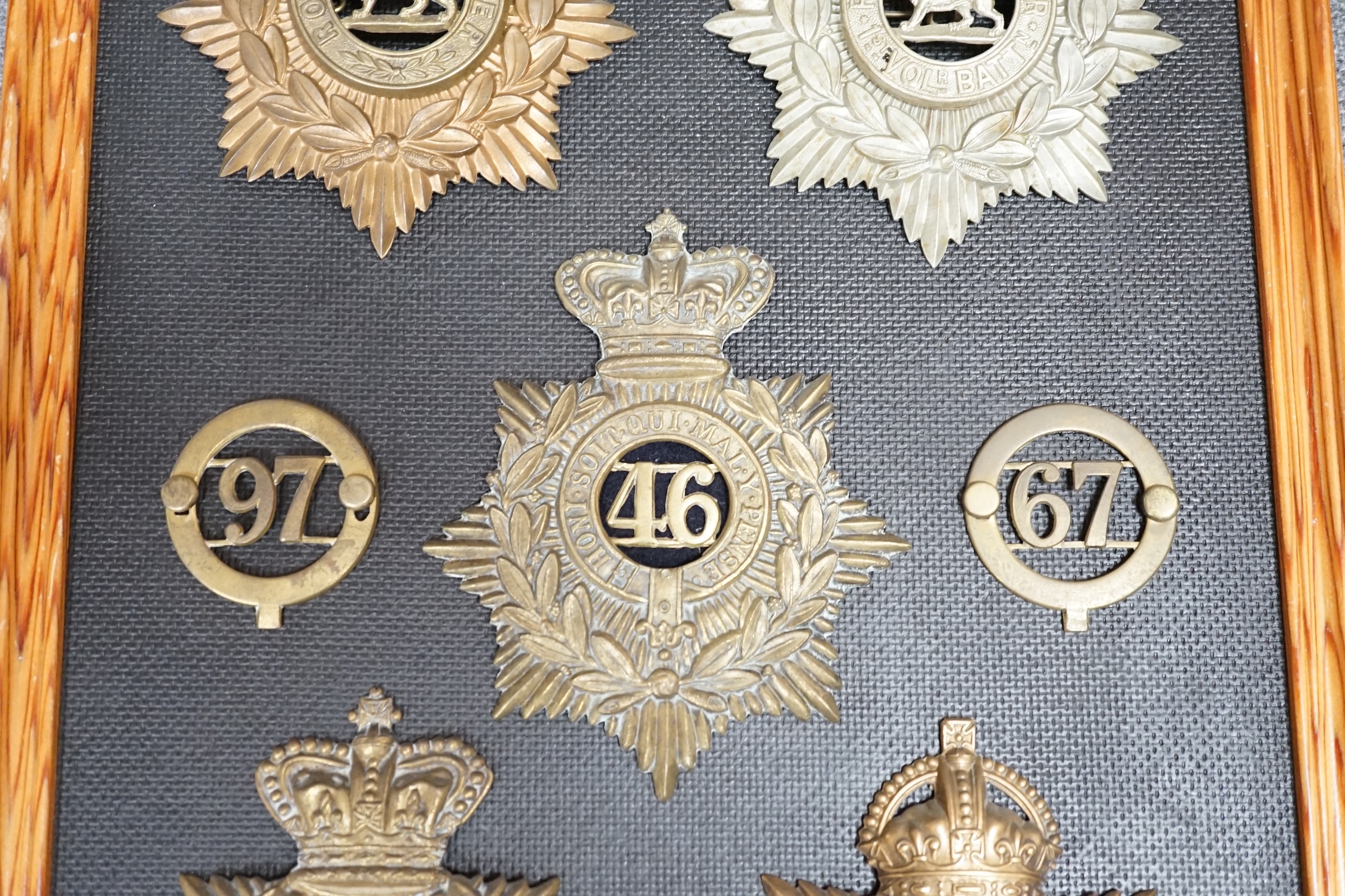 Five military helmet plates and two other centre badges mounted on a board, including; the Royal Lancashire Regiment, the Royal Lancashire 1st Volunteer Battalion, the Oxfordshire Regiment, the Royal Sussex Regiment, etc